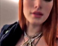 Bella Thorne with red hair and showing cleavage in a dress